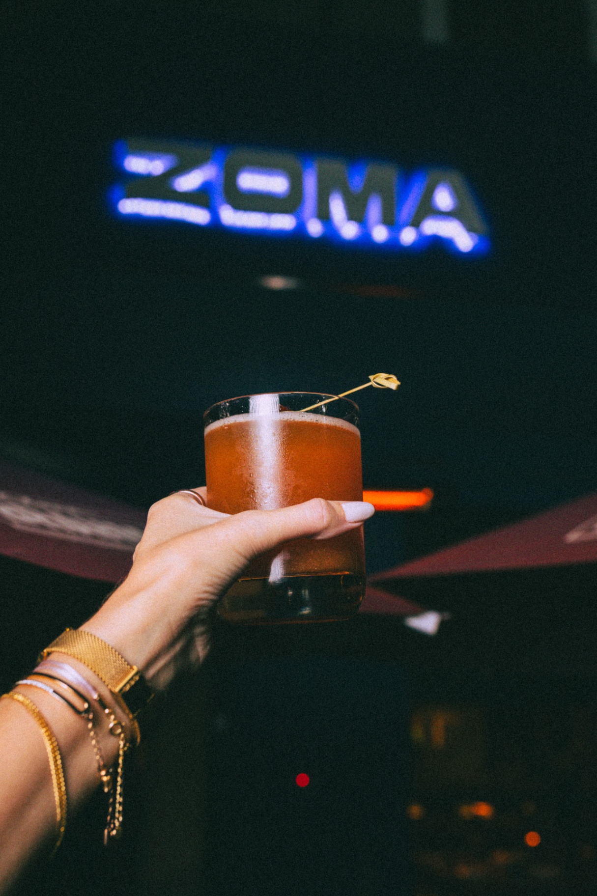 Drink autoral com o letreiro ZOMA ao fundo